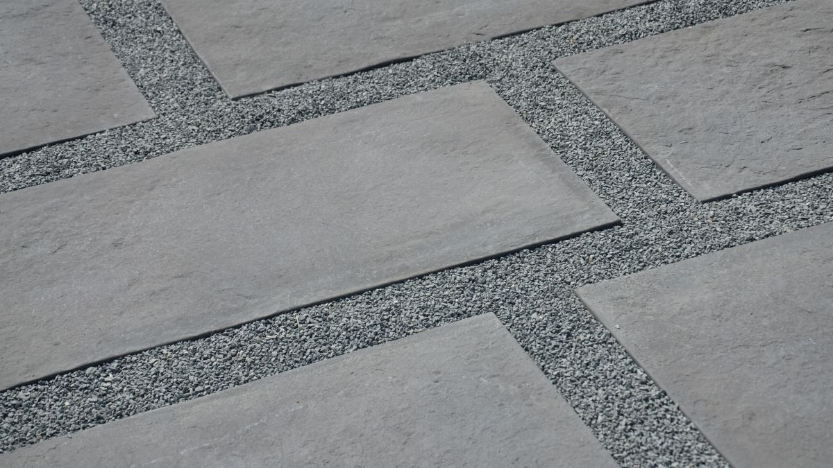 Graue rechteckige Terrassenplatten aus Naturstein, verlegt im Versatz mit hellem Splitt in den Fugen