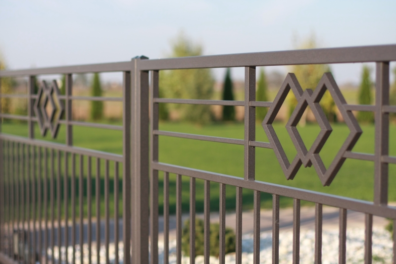 Nahaufnahme eines eleganten Metallzauns mit dekorativen Rautenmustern vor einem unscharfen grünen Gartenhintergrund