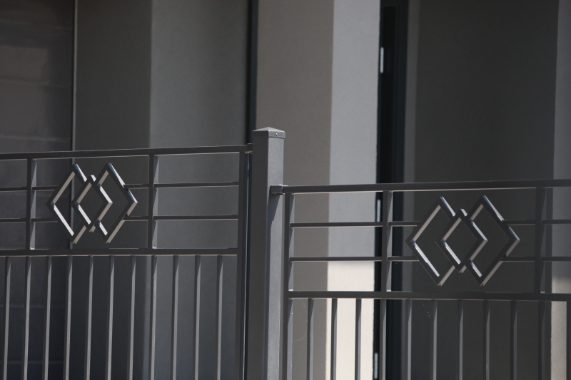 Graues Metallgeländer eines Balkons mit dekorativen geometrischen Rauten-Mustern in minimalistischem Stil