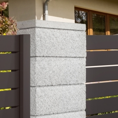Grauer Betonpfosten mit dunklem Metallzaun, eine moderne Gartengestaltung im minimalistischen Stil.