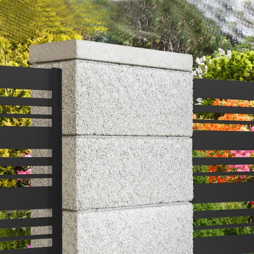 Grauer Betonpfeiler aus drei Blöcken mit schwarzen horizontalen Metallzaunelementen vor einem Garten